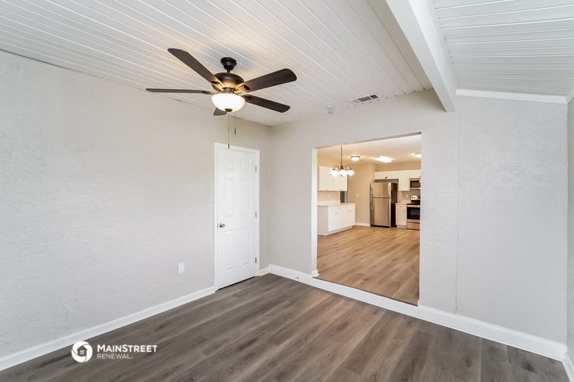 the living room and dining room of a renovated house with a ceiling fan