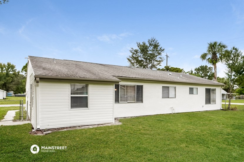 a small white house with a grassy yard and a palm tree