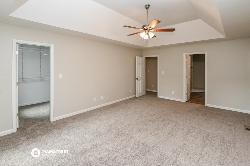 the spacious living room with ceiling fan and carpeting