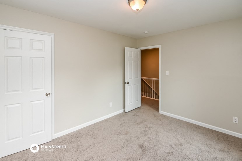 a bedroom with a door and a hallway with a staircase