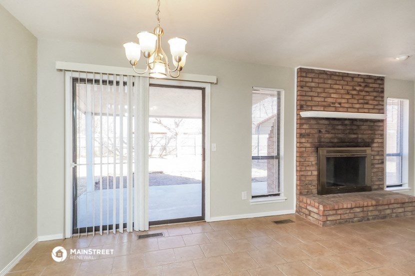an empty living room with a brick fireplace and a sliding glass door