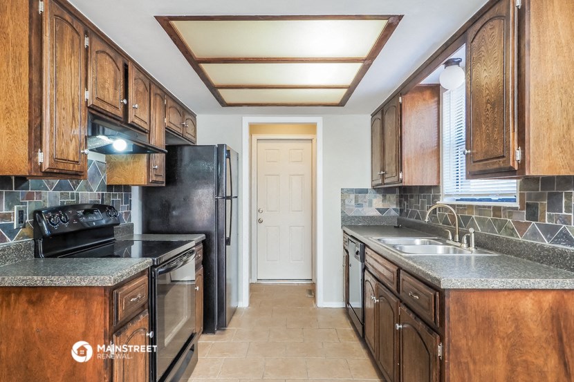 a kitchen with wooden cabinets and a black refrigerator
