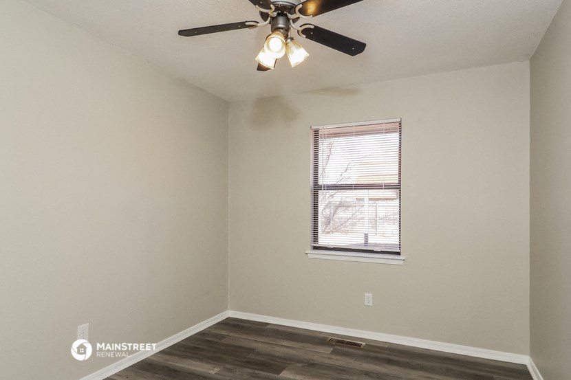 the bedroom of an apartment with a ceiling fan and a window