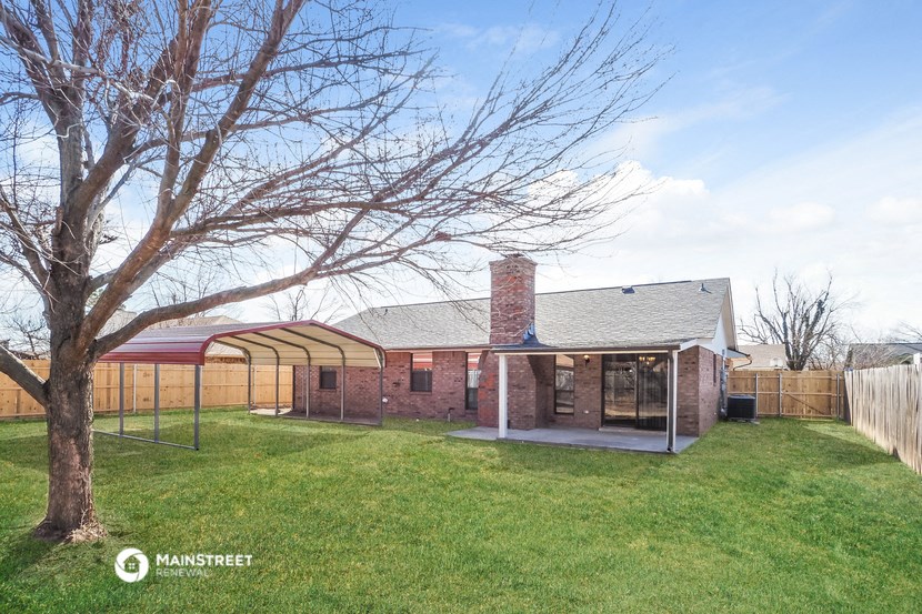the backyard of a brick house with a yard and a tree