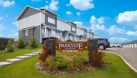 A sign for Parkside Townhomes stands in front of a building.
