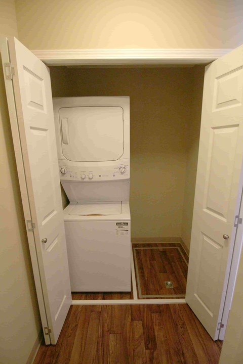 A white dishwasher and dryer are stacked in a small space.