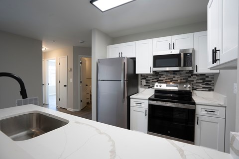 a kitchen with white cabinets and stainless steel appliances and a sink