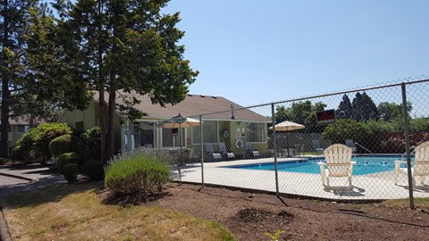 a backyard with a swimming pool and a house behind a fence
