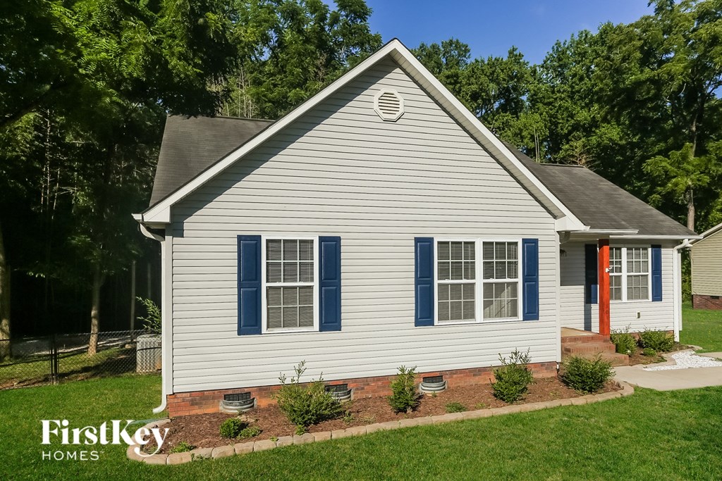 a blue and with blue shutters and a front yard with a garden