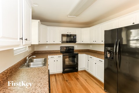 a kitchen with white cabinets and black appliances