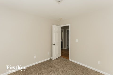 a bedroom with beige carpet and a door to a hallway