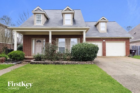 the front of a brick house with white garage doors