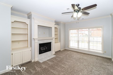 a living room with a fireplace and shelves and a ceiling fan