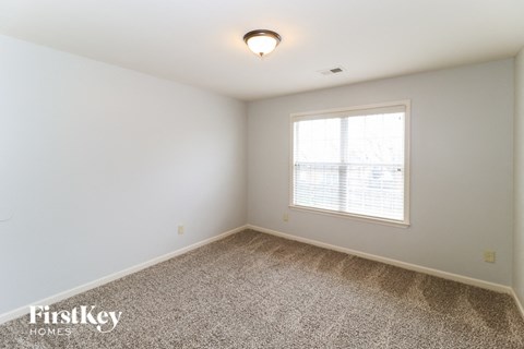 a bedroom with a large window and a carpeted floor