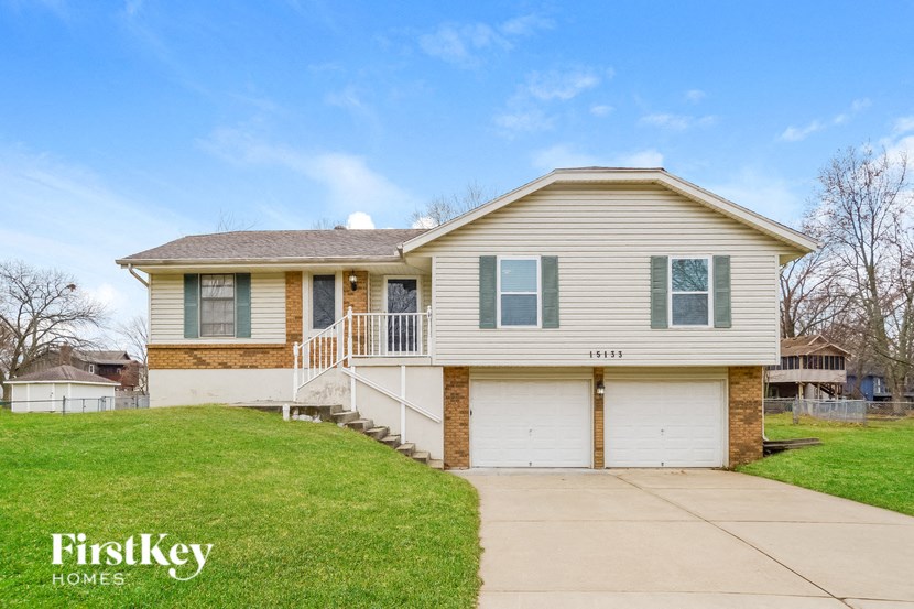 a beige and brown house with a driveway and grass