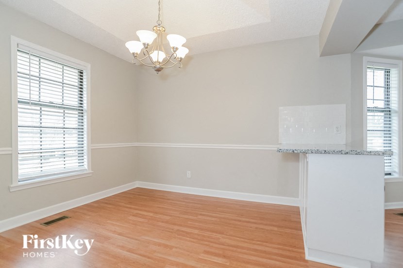 an empty dining room and kitchen with wood flooring and a chandelier