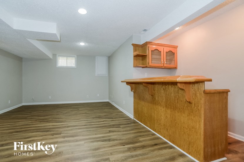 a living room with a bar and a gray wall and wood floors