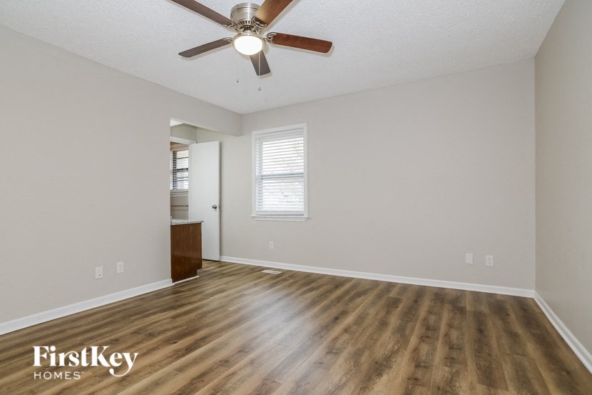 an empty living room with wooden floors and a ceiling fan