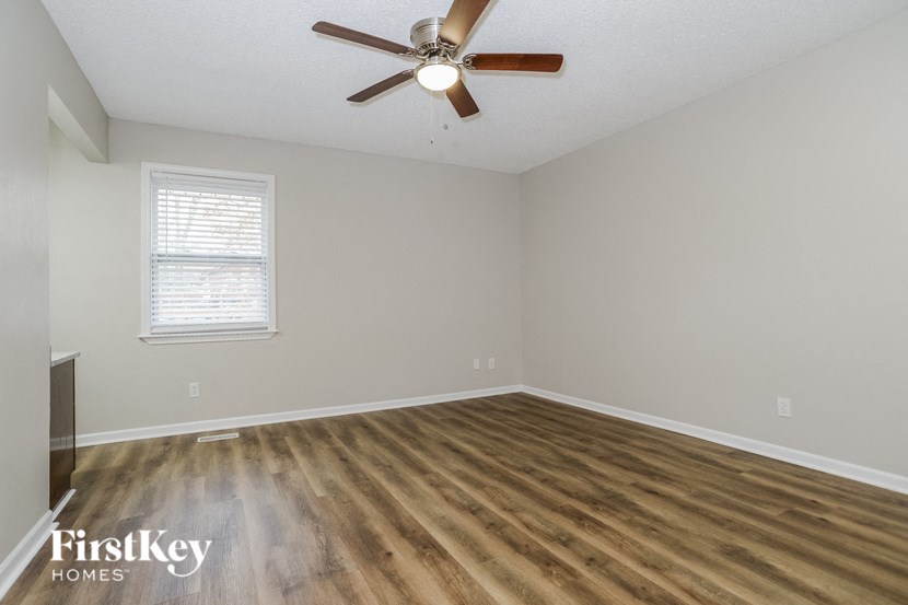 an empty living room with wood flooring and a ceiling fan