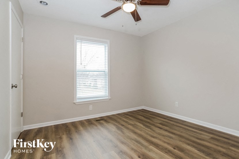 an empty bedroom with wood flooring and a ceiling fan