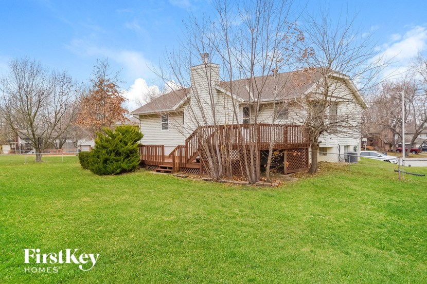 a white house with a deck on the side of a yard
