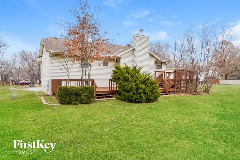 a white house with a yard and a wooden deck