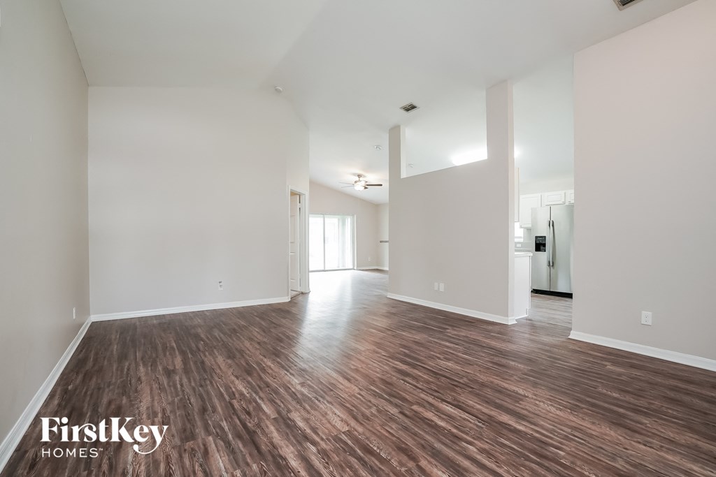 A spacious room with wooden flooring and white walls, branded with "FirstKey Homes".