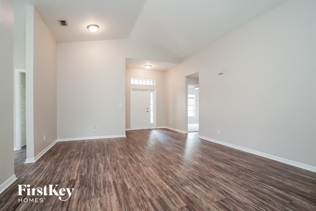 A spacious room with wooden flooring and white walls, branded with "FirstKey Homes".