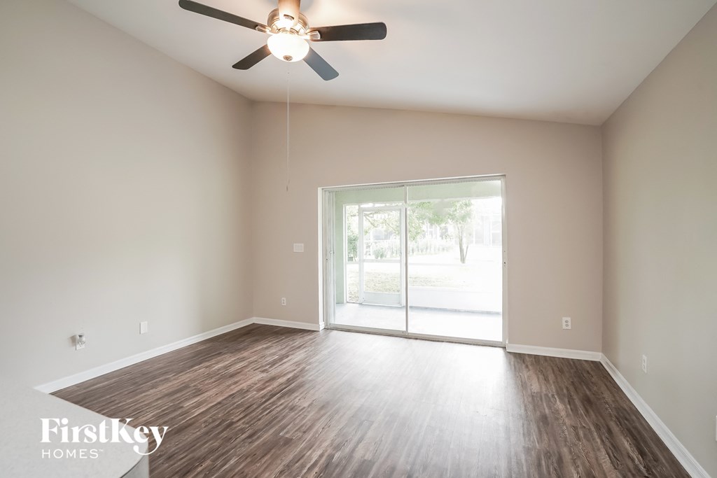 A room with a ceiling fan and sliding glass doors.
