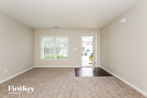 a spacious living room with carpet and a door to a patio
