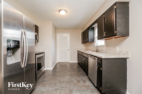 A kitchen with a refrigerator, microwave, oven, and sink.