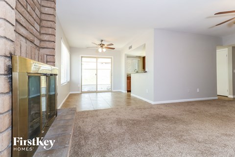A spacious room with a carpeted floor and a ceiling fan.