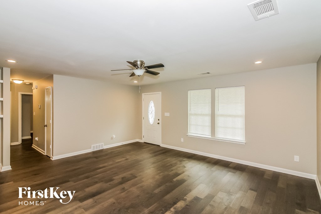 the living room with wood flooring and a ceiling fan