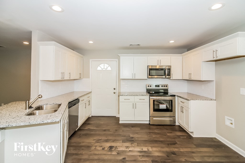 a white kitchen with white cabinets and stainless steel appliances