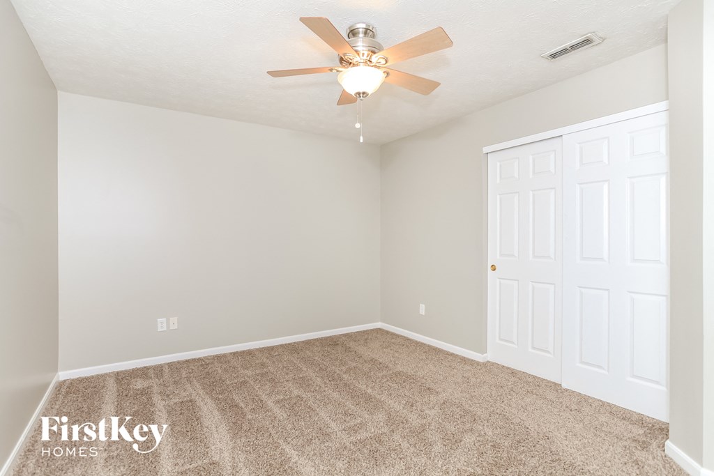 the spacious living room with carpet and a ceiling fan