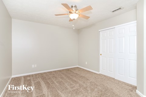 the spacious living room with carpet and a ceiling fan