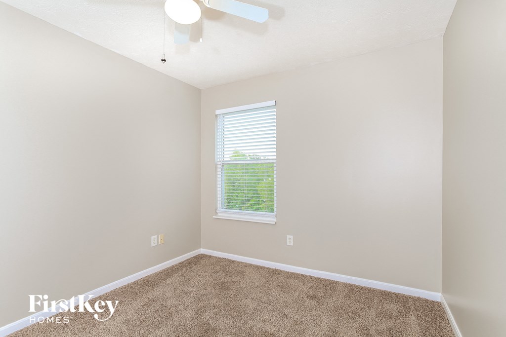 a bedroom with carpet and a window and a ceiling fan