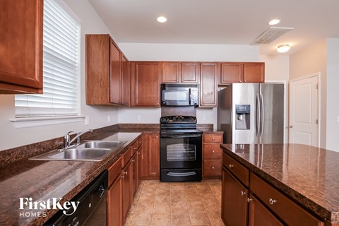 A kitchen with brown cabinets and a black stove top oven.
