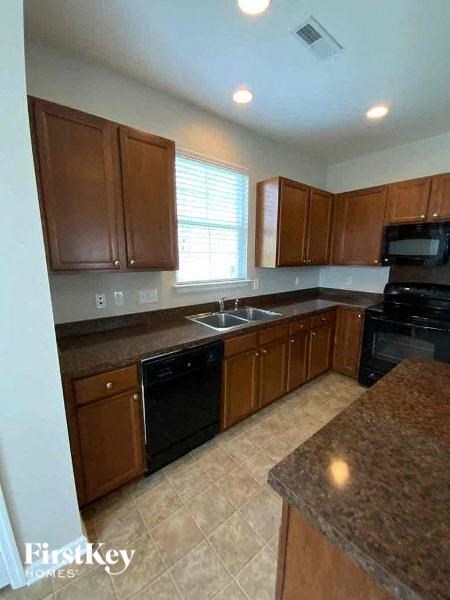A kitchen with brown cabinets and black appliances.