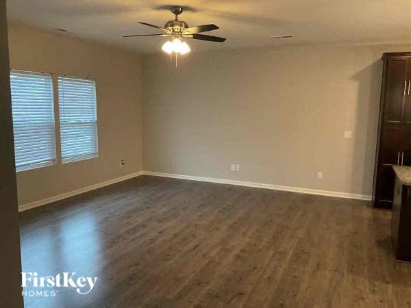 an empty living room with a ceiling fan and wood floors