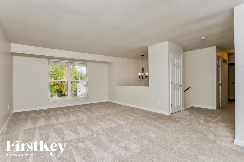 an empty living room with a white door and a window