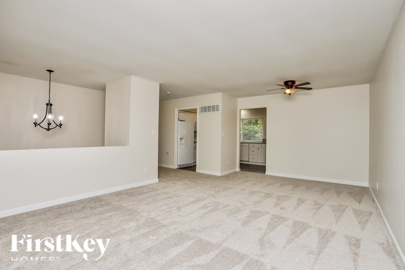 an empty living room with white walls and a ceiling fan