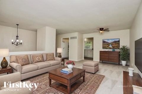 A living room with a beige couch, a coffee table, and a painting on the wall.