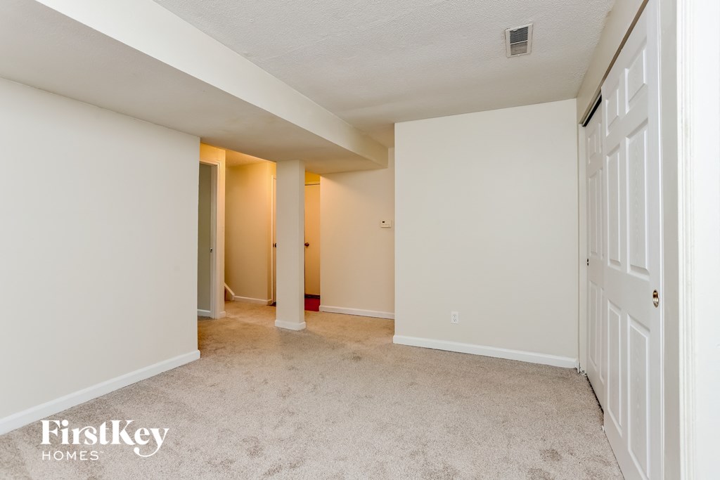 a bedroom with white walls and carpet and a closet