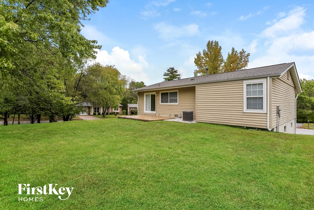 a small brown house on a grassy yard with trees