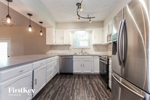 A kitchen with a stainless steel refrigerator and wooden floors.
