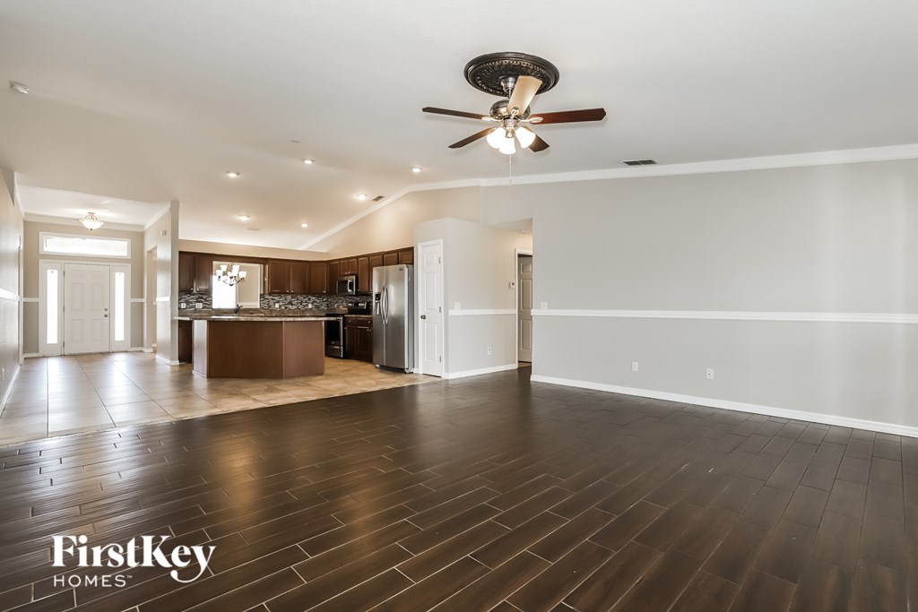 A spacious room with wooden floors and a ceiling fan.