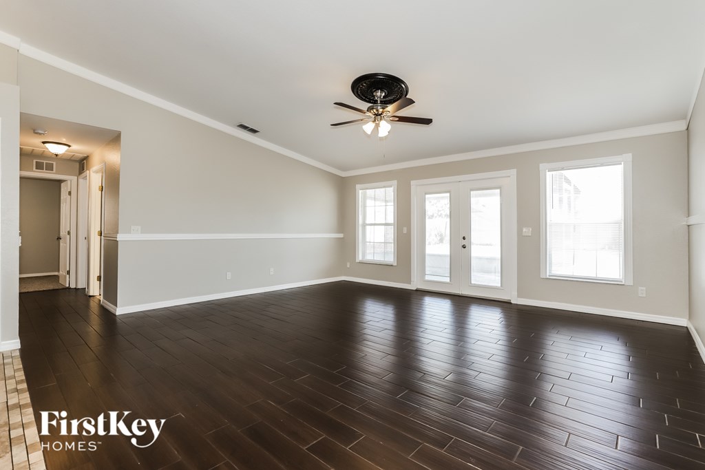 A spacious room with wooden floors and a ceiling fan.
