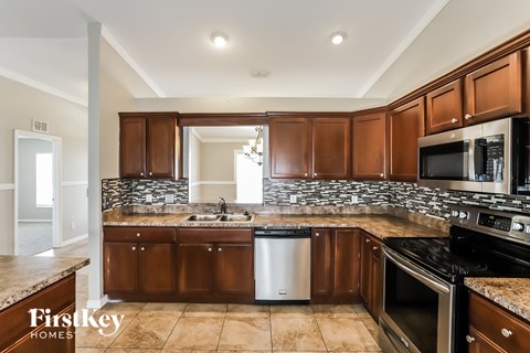 A kitchen with brown cabinets and a stone backsplash.