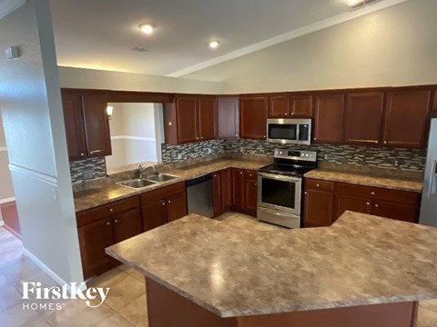 A kitchen with brown cabinets and a stone backsplash.